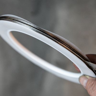 Hand hält eine ringförmige PTFE-Flachdichtung mit metallischer Kernlage in die Kamera