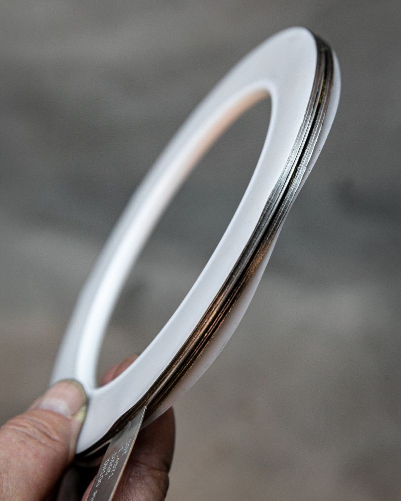 Hand hält eine ringförmige PTFE-Flachdichtung mit metallischer Kernlage in die Kamera